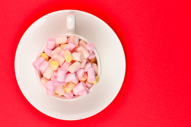 Tasse mit Marshmallow auf rotem Grund. Platz kopieren.