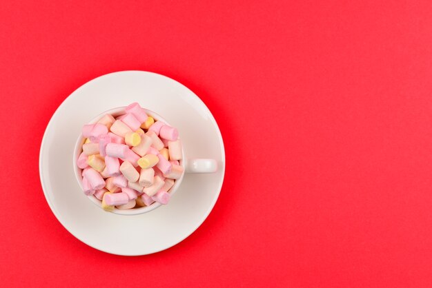 Tasse mit Marshmallow auf rotem Grund. Speicherplatz kopieren.