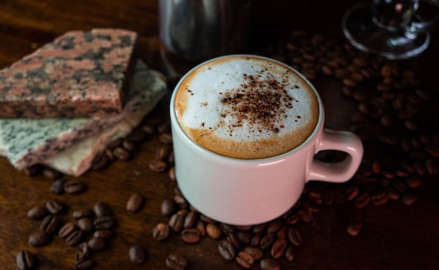 Tasse mit Milchschaum und Funken von Kakao und Kaffeebohnen