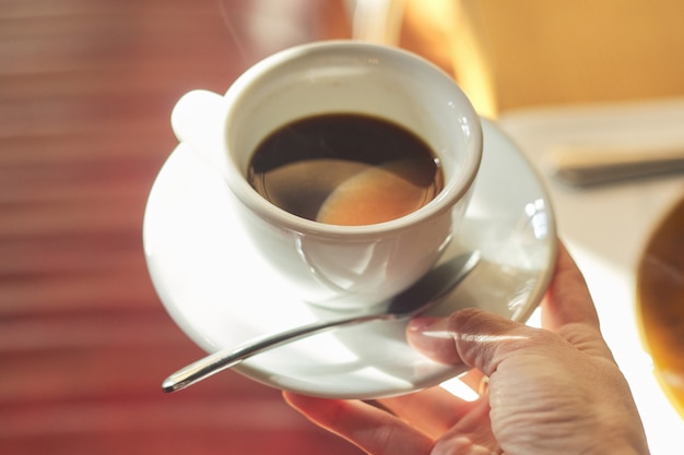 Tasse mit Morgenkaffee in weiblicher Hand