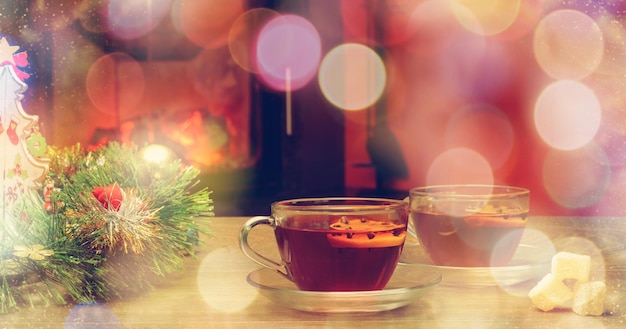 Tasse mit Weihnachtsschmuck in der Nähe des Kamins Winterurlaubskonzept Tasse heißes Getränk vor dem warmen Kamin Gemütliche entspannte magische Atmosphäre