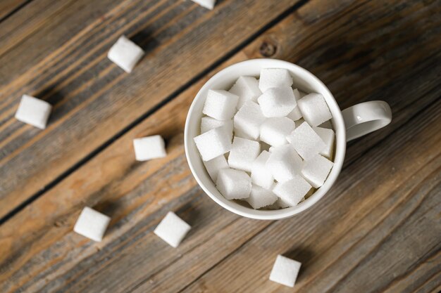 Tasse mit Zuckerwürfeln auf einer Holzoberfläche in Nahaufnahme