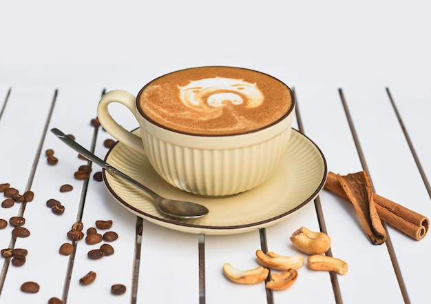 Tasse Nuss-Cappuccino mit Löffel und Zucker auf hölzerner weißer Tischseitenansicht