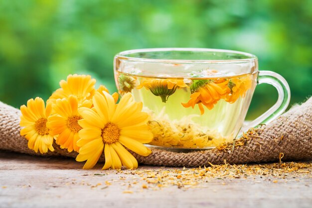 Tasse Ringelblumentee und Ringelblumen im Freien auf grünem HintergrundxAxA