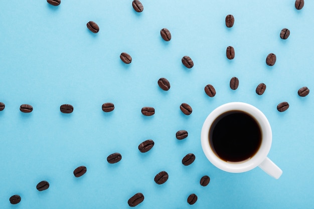 Tasse schwarzen Kaffee und Kaffeebohnen auf blauem Hintergrund