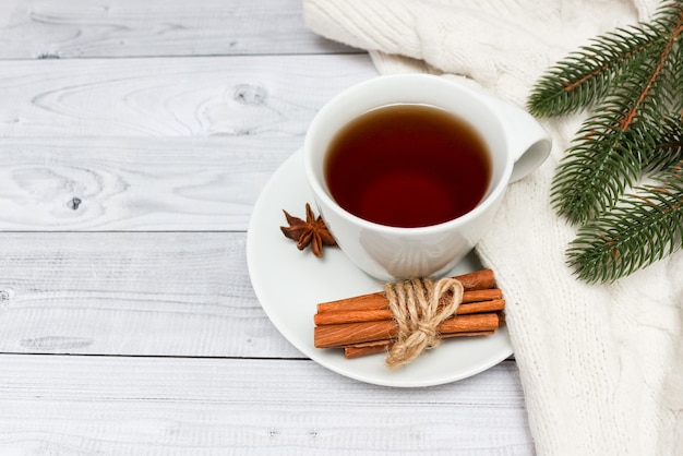 Tasse schwarzen tee mit schal bedeckt. weihnachtsbaum im hintergrund. winterkonzept.