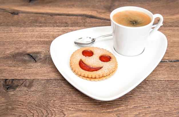 Tasse schwarzer Kaffee mit gelächeltem Plätzchen Lustiges Frühstück