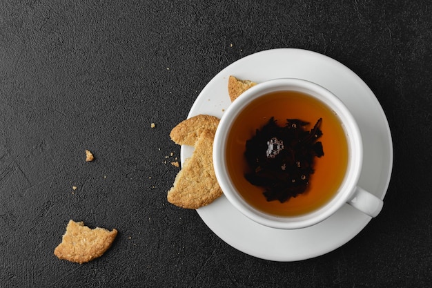 Tasse schwarzer Tee mit Kekse auf dunklem Hintergrund