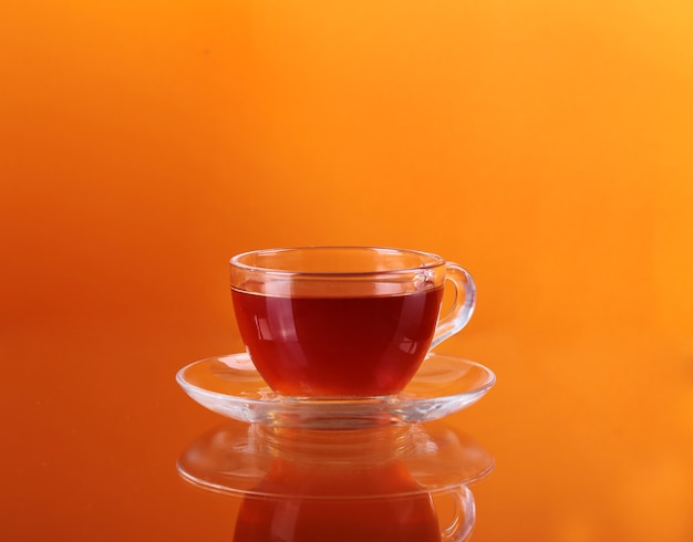 Tasse Tee auf Glas mit orange Wand