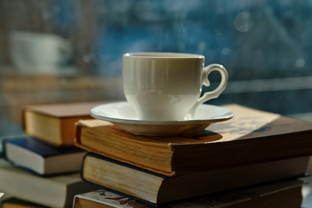 Tasse Tee, ein Stapel Bücher am Fenster