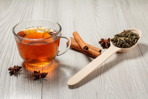 Tasse Tee Holzlöffel mit Blättern von grünem Tee und Zimt