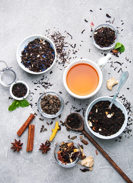 Tasse Tee mit aromatischem trockenem Tee in den Schüsseln