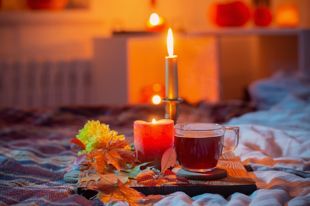 Tasse Tee mit brennenden Kerzen im Schlafzimmer