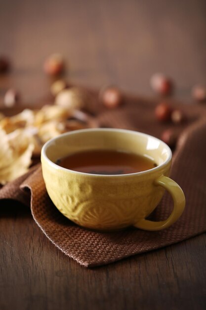 Tasse Tee mit Herbstdekor auf Holztisch