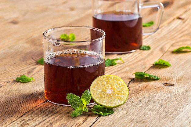 Tasse tee mit ingwer, zitrone und minze auf holztisch