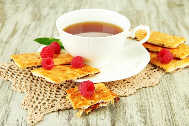 Tasse Tee mit Kekse und Himbeeren auf dem Tisch in Nahaufnahme