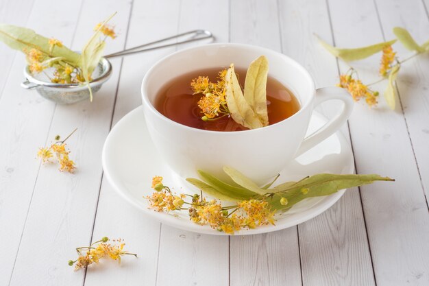 Tasse Tee mit Lindenblumen auf einem Leuchtpult