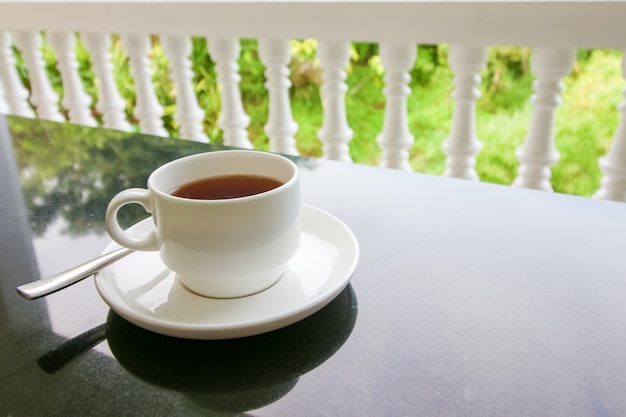 Tasse tee mit löffel und platte auf der schwarzen tabelle