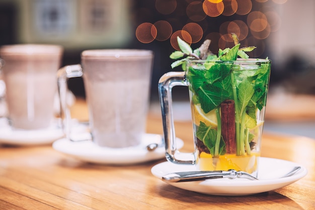 Tasse Tee mit Minze, Zimt und Zitrone der weißen Platte