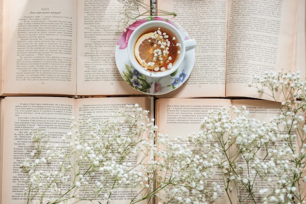 Tasse Tee mit Zitrone und geöffnetes Buch auf dem Tisch im Zimmer