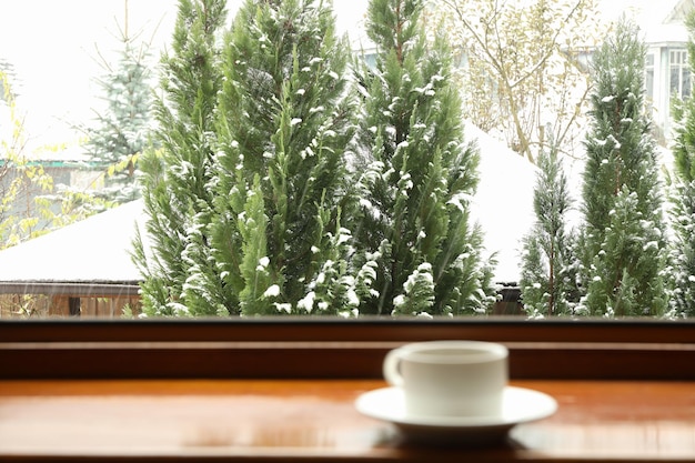 Tasse Tee steht auf hölzerner Fensterbank