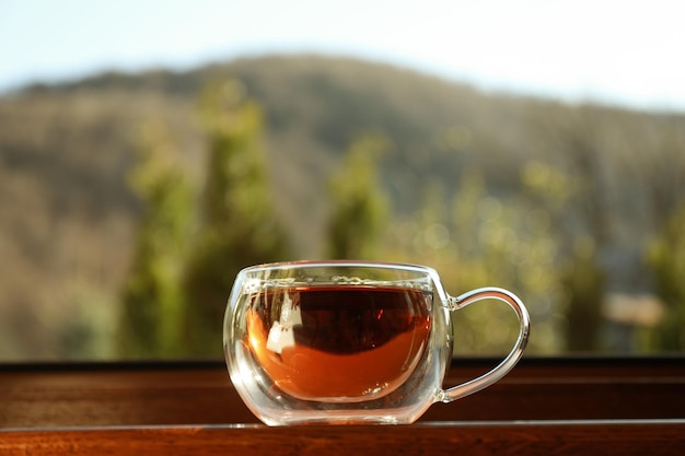 Tasse Tee steht auf hölzerner Fensterbank