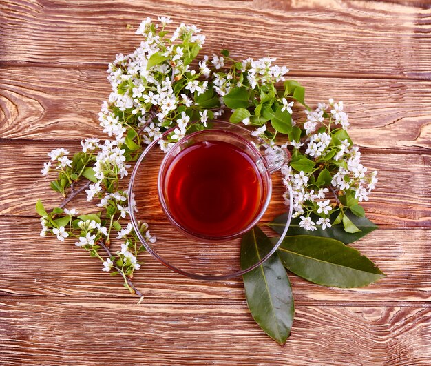 Tasse Tee und Blumen auf einem Holztisch