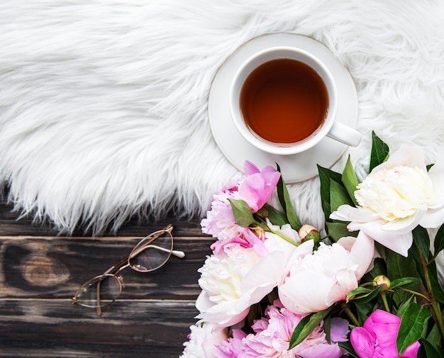 Tasse Tee und rosa Pfingstrosen