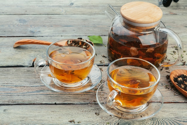 Tasse Tee und Teeblätter auf Holztisch