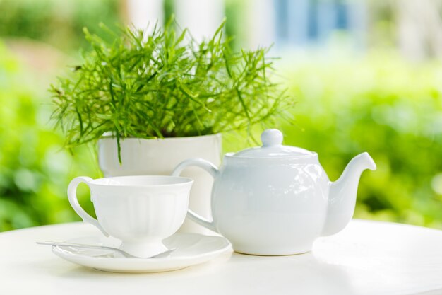 Tasse Tee und Teekanne auf einem unscharfen Hintergrund der Natur