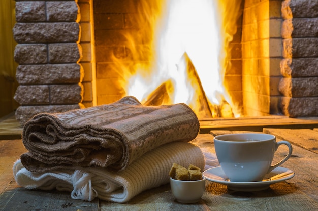 Tasse Tee und Zucker, Wollsachen in der Nähe von gemütlichem Kamin, Landhaus, Winterferien