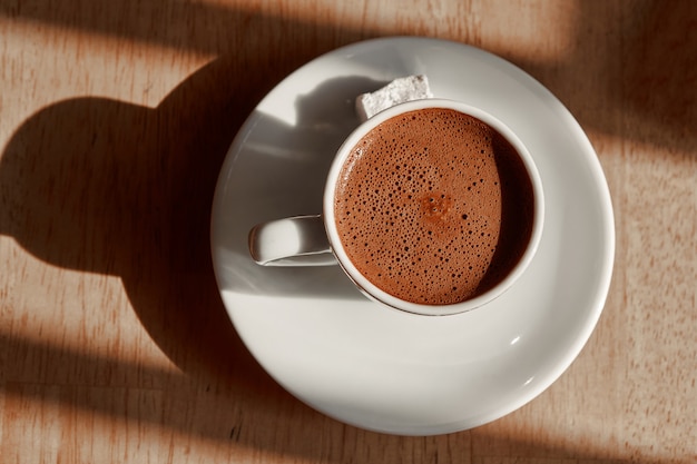 Tasse türkischen Kaffees mit Schaum lokalisiert auf einem hölzernen braunen Tisch