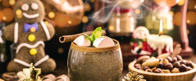 Tasse vegane heiße Schokolade, dampfendes und rauchiges Heißgetränk, serviert zu Weihnachten und Neujahr mit Kakao, Zimt, Haselnuss und Kastanien
