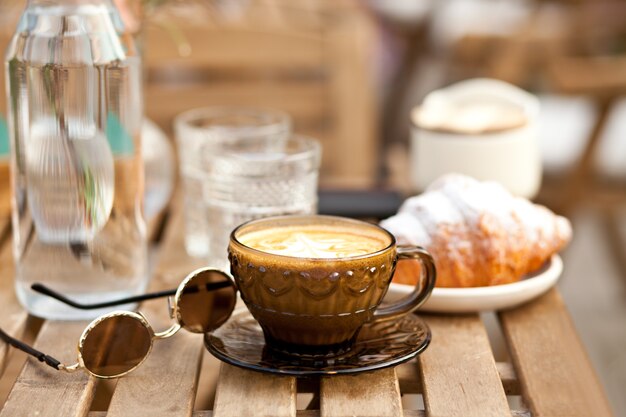 Tassen Cappuccino-Kaffee mit Croissant in einem Café