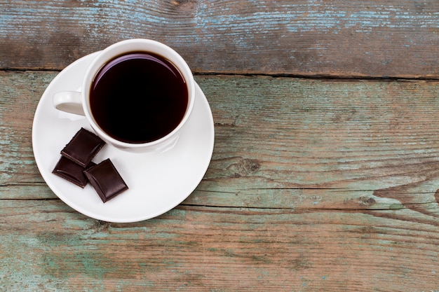 Tassen Kaffee mit Schokolade auf Holztisch mit Kopienraum.