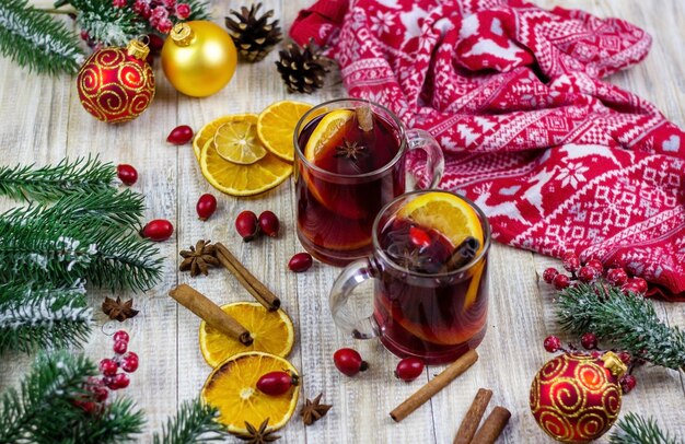 Tassen mit heißem Glühwein auf einem hölzernen Hintergrund. Neujahrskonzept