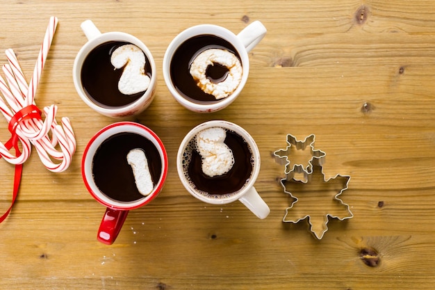 Tassen mit heißer Schokolade, garniert mit weißen Marshmallows auf Holztisch.