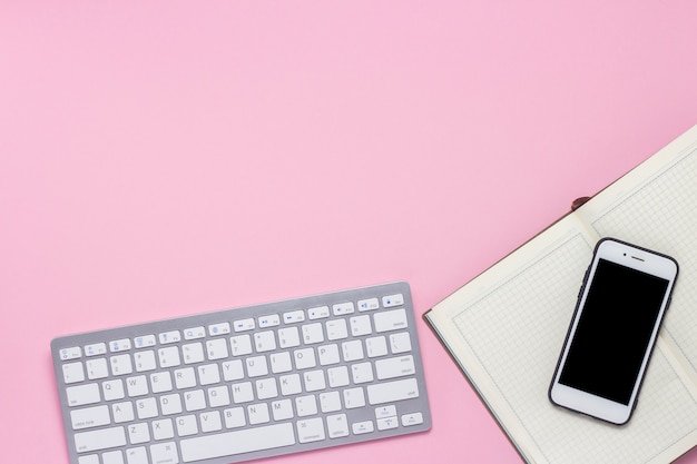 Tastatur, Handy und Tagesprotokoll auf einem rosa Hintergrund. Geschäftskonzept. Flache Lage, Draufsicht.