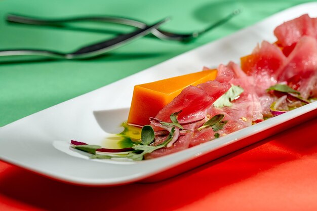 Tataki de atún con cebolla y calabaza en un plato blanco con fondos brillantes. Cocina japonesa. Enfoque selectivo, sombras duras