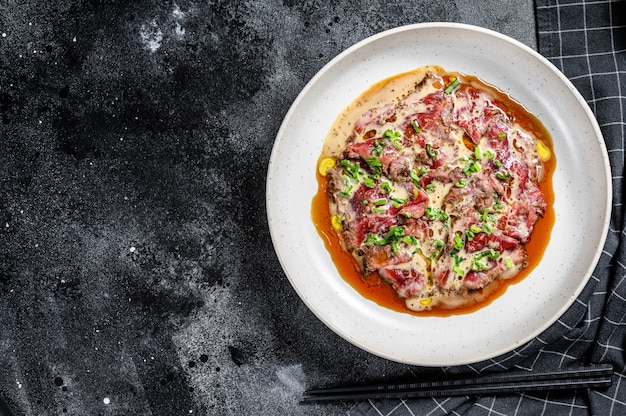 Tataki de ternera con cebolla verde fresca. fondo negro. Vista superior. Copia espacio