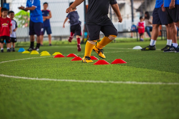 Foto táticas de bola de futebol em campo de grama com barreira para treinar habilidades de salto de crianças na academia de futebol