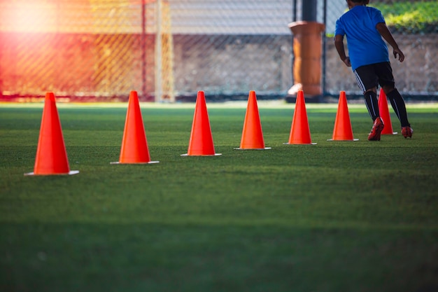 Táticas de bola de futebol no campo de grama com barreira para treinar habilidades de salto de crianças na academia