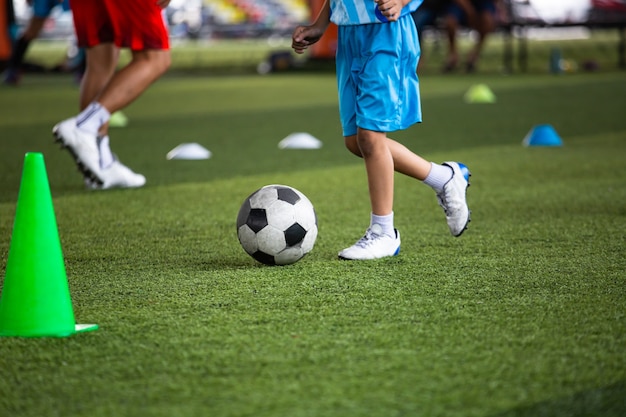 Táticas de bola de futebol no campo de grama com cone para fundo de treinamento. Treinamento de crianças na academia de futebol