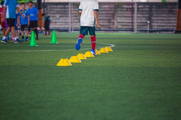 Táticas de bola de futebol no campo de grama com cone para treinamento em segundo plano.