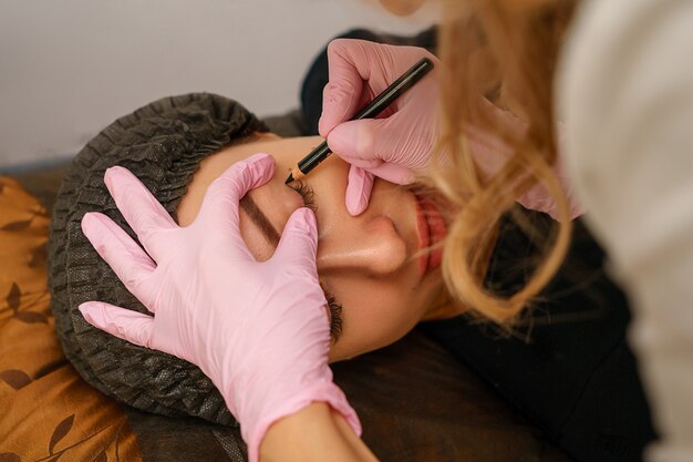 Tattoo Master hace que el cliente tatúe cejas y labios.