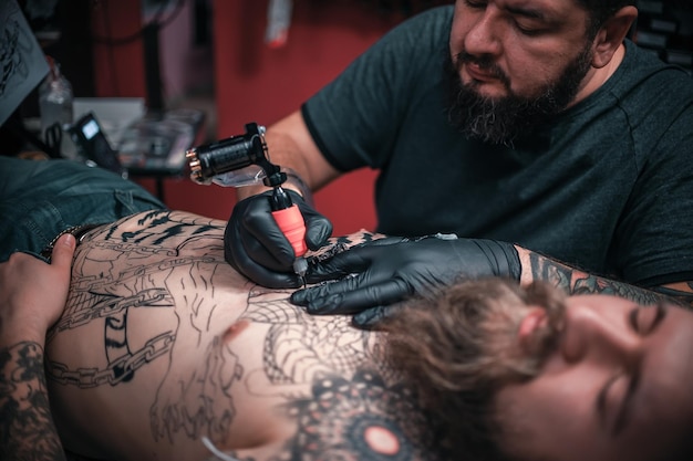 Tattoo-Spezialist, der im Salon an einem professionellen Tattoo-Maschinengewehr arbeitet.