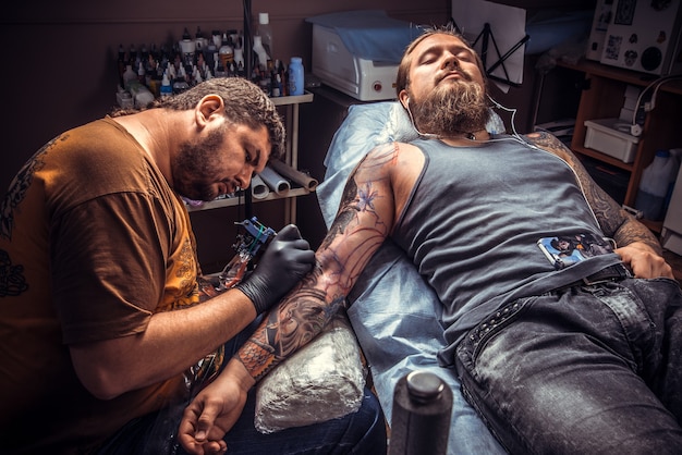 Tattooer mostrando o processo de fazer uma tatuagem no estúdio de tatuagem