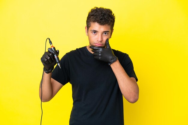 Tatuador brasileiro homem isolado em fundo amarelo pensando