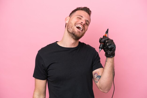 Tatuador brasileiro homem isolado no fundo rosa rindo