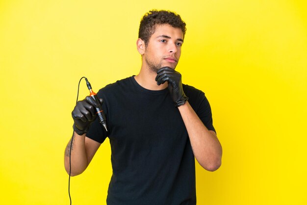 Foto tatuador brasileiro isolado em fundo amarelo e olhando para cima